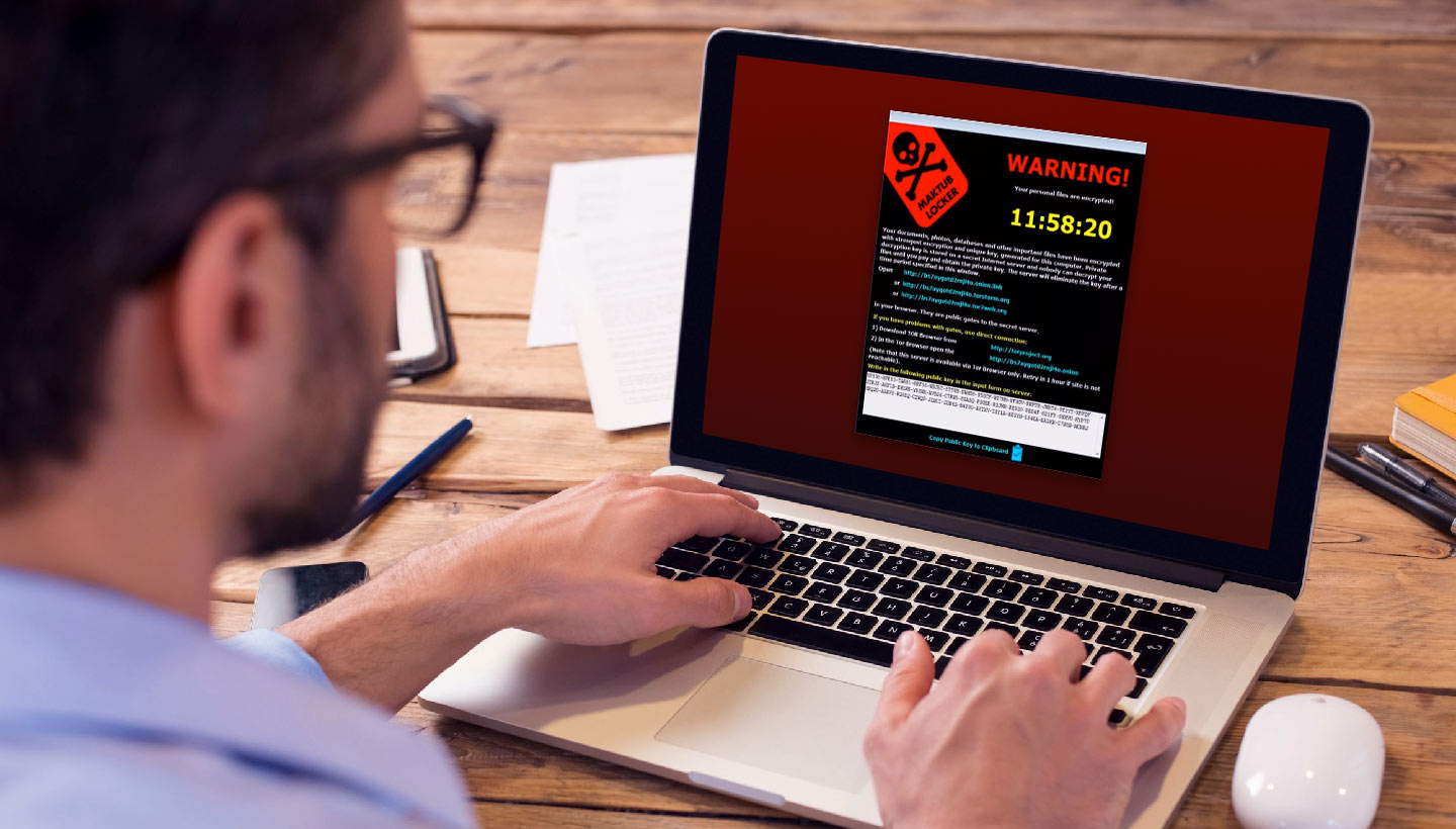 Stronger Cybersecurity Protections man working on a laptop with a ransomware demand message
